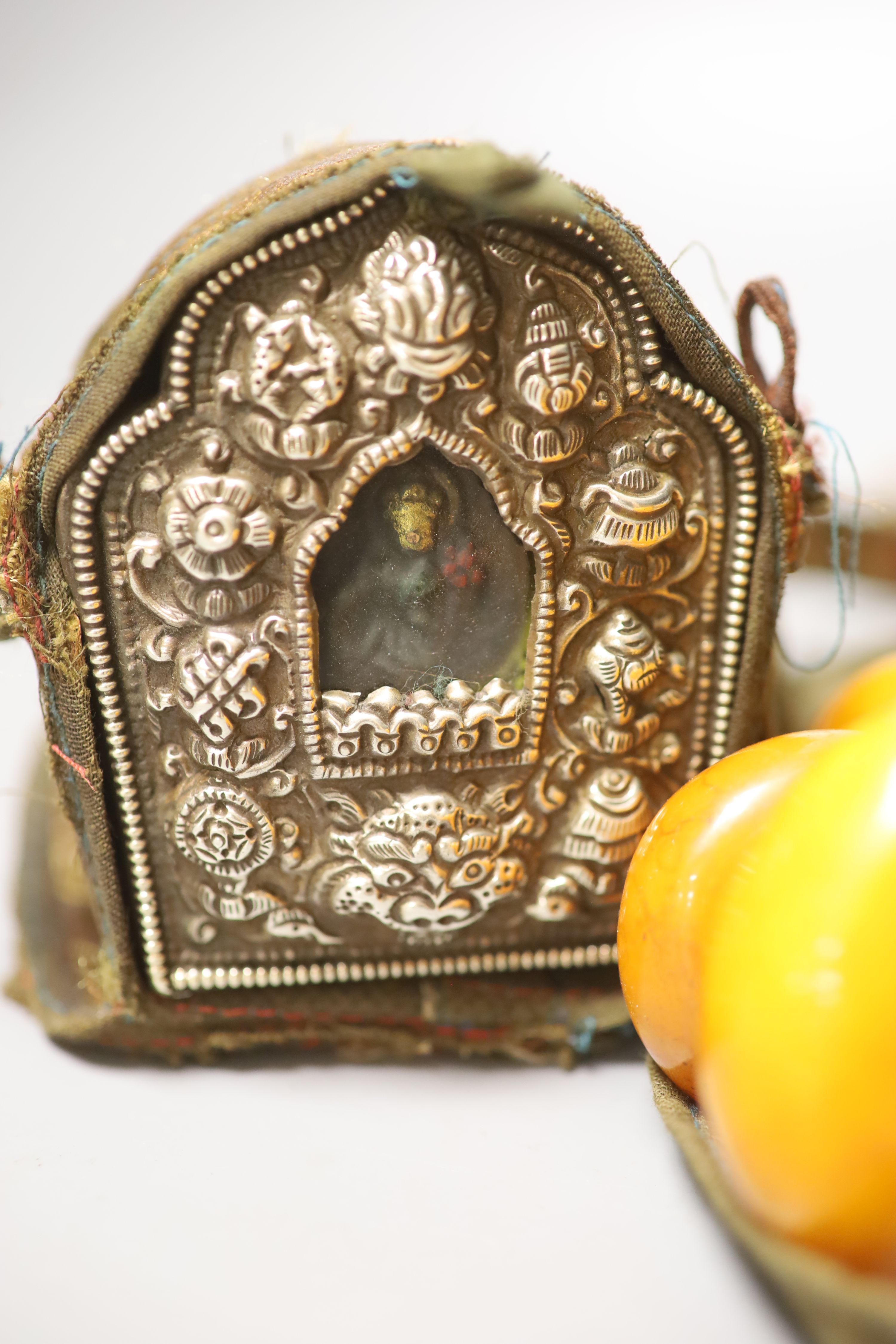 An early 20th century Tibetan and white metal portable shrine and a simulated amber Buddhist rosary